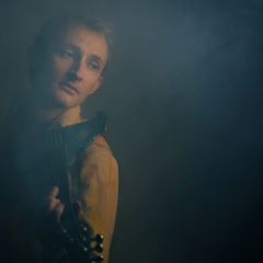Musician in a smoky room holding an electric violin
